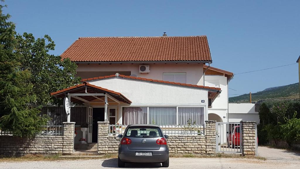 une petite voiture garée devant une maison dans l'établissement Sobe Braica, à Drniš