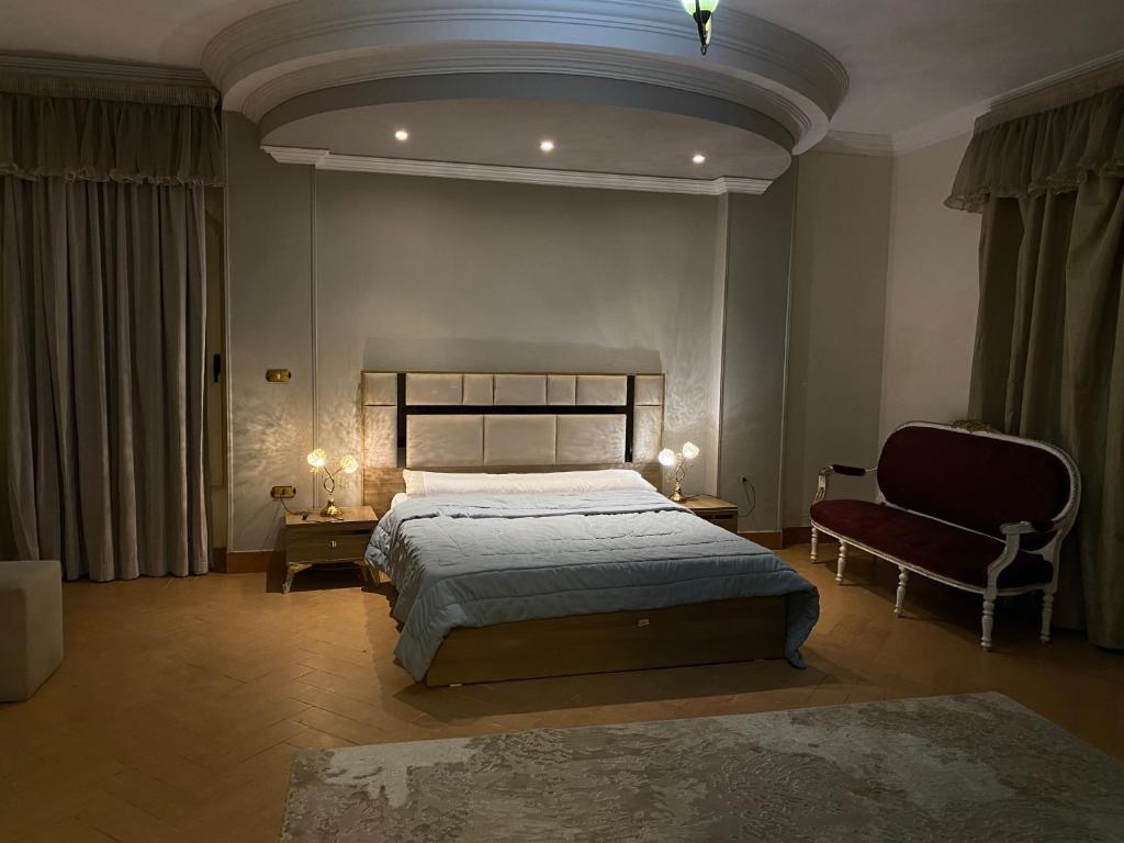 a bedroom with a large bed and a chair at The Gardenia Villa Chic Escape with Pool in 6th Of October