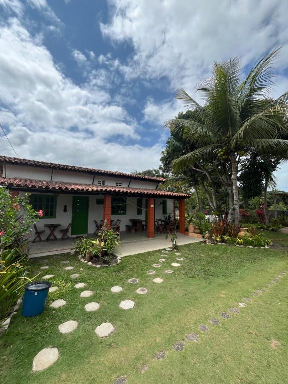 une maison avec une cour avec des rochers dans l'herbe dans l'établissement Pousada Canto da Reg, à Santa Cruz Cabrália