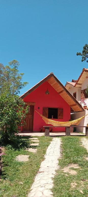 a red building with a pathway leading to it at Hospedagem Refúgio dos Gnomos in Visconde De Maua
