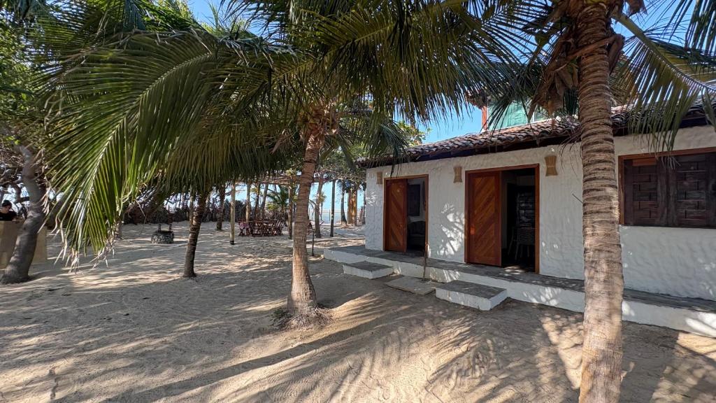 a small building on the beach with palm trees at Casa Monan, Atins beach in Atins