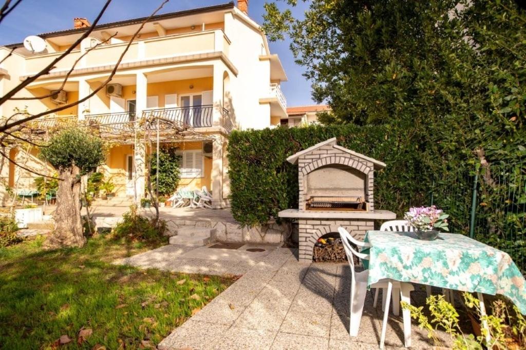 a backyard with a table and a grill and a house at Apartments with parking space Lopar, Rab - 24754 in Lopar