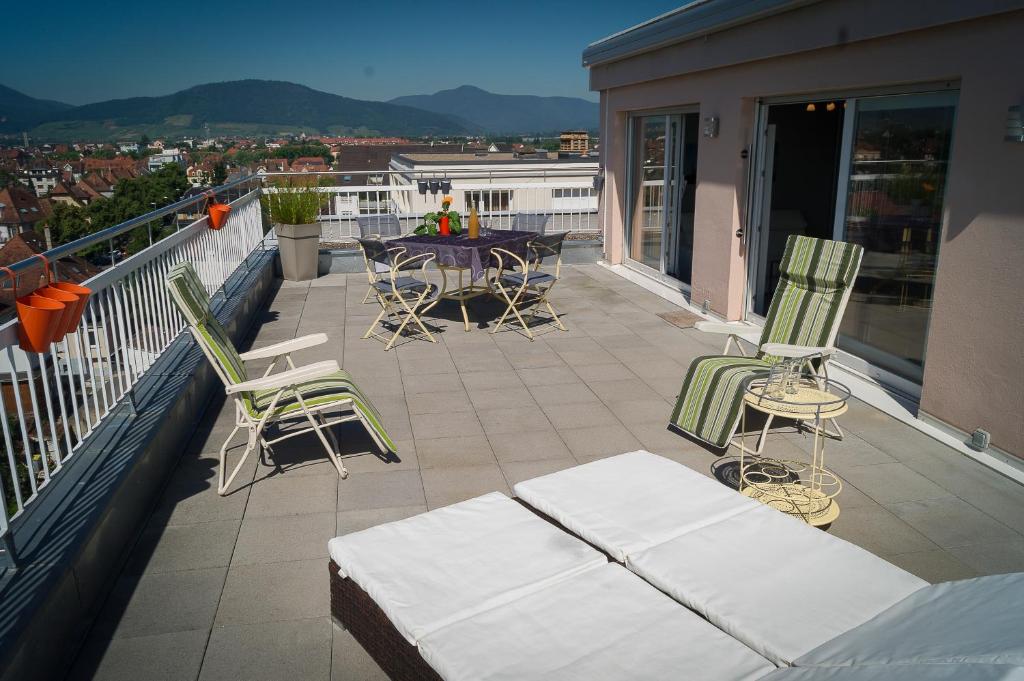 a balcony with chairs and a table on a roof at En attique - Residence le Ronsard in Sélestat