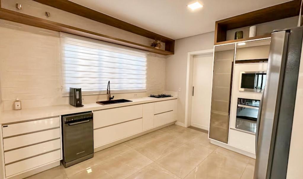 a kitchen with white cabinets and a refrigerator and a window at Casa alto padrão com piscina em Foz in Foz do Iguaçu