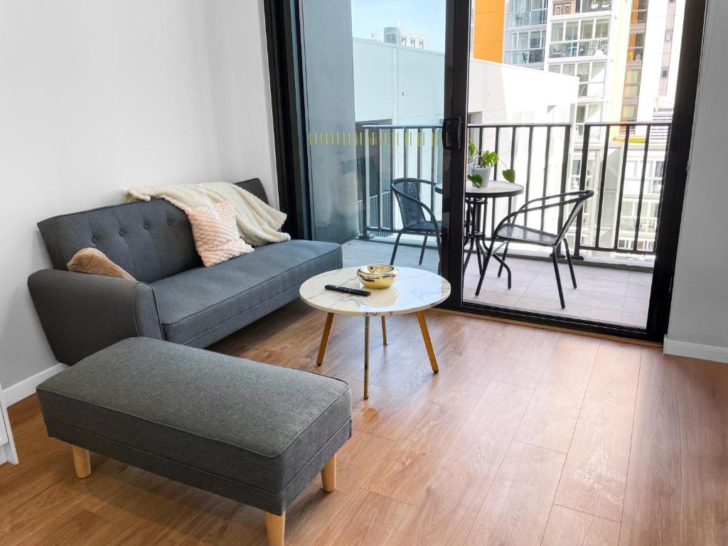 d'un salon avec un canapé et une table ainsi que d'un balcon. dans l'établissement The Cullinan Apartments by CLLIX, à Adélaïde