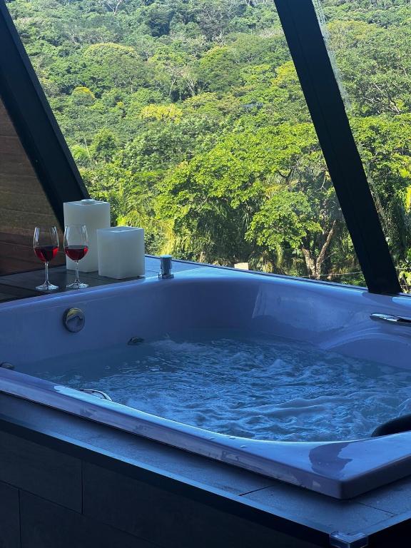 a bath tub with two glasses of wine at Chalé Mirante Morro dos Ventos in Chapada dos Guimarães