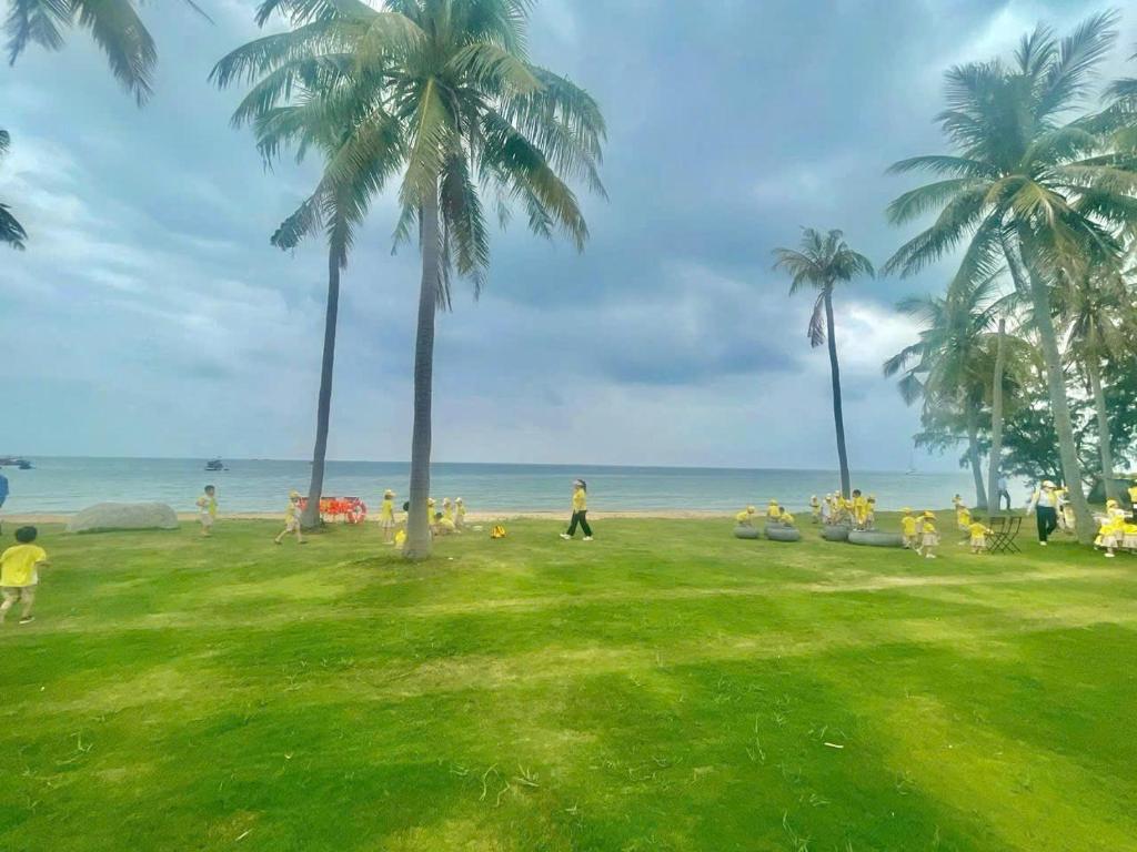 a group of people on a beach with palm trees at The Kind Villas Phu Quoc in Phu Quoc
