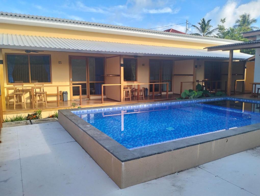 a swimming pool in front of a house at Villa Santai Mentawai in Tuapejat