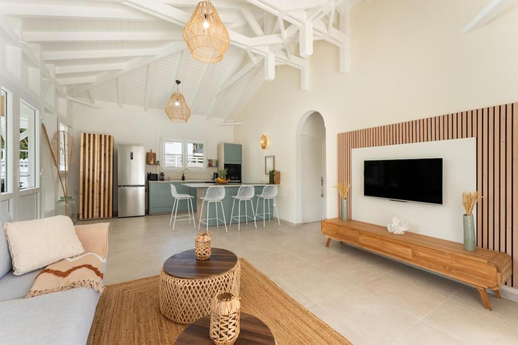 a living room with a couch and a tv at Villa Azura - Accès mer & piscine privée in Le Moule