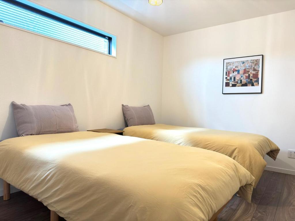 Dos camas una al lado de la otra en una habitación. en The YAMAGUCHI山口Golf Residence, en Inzai