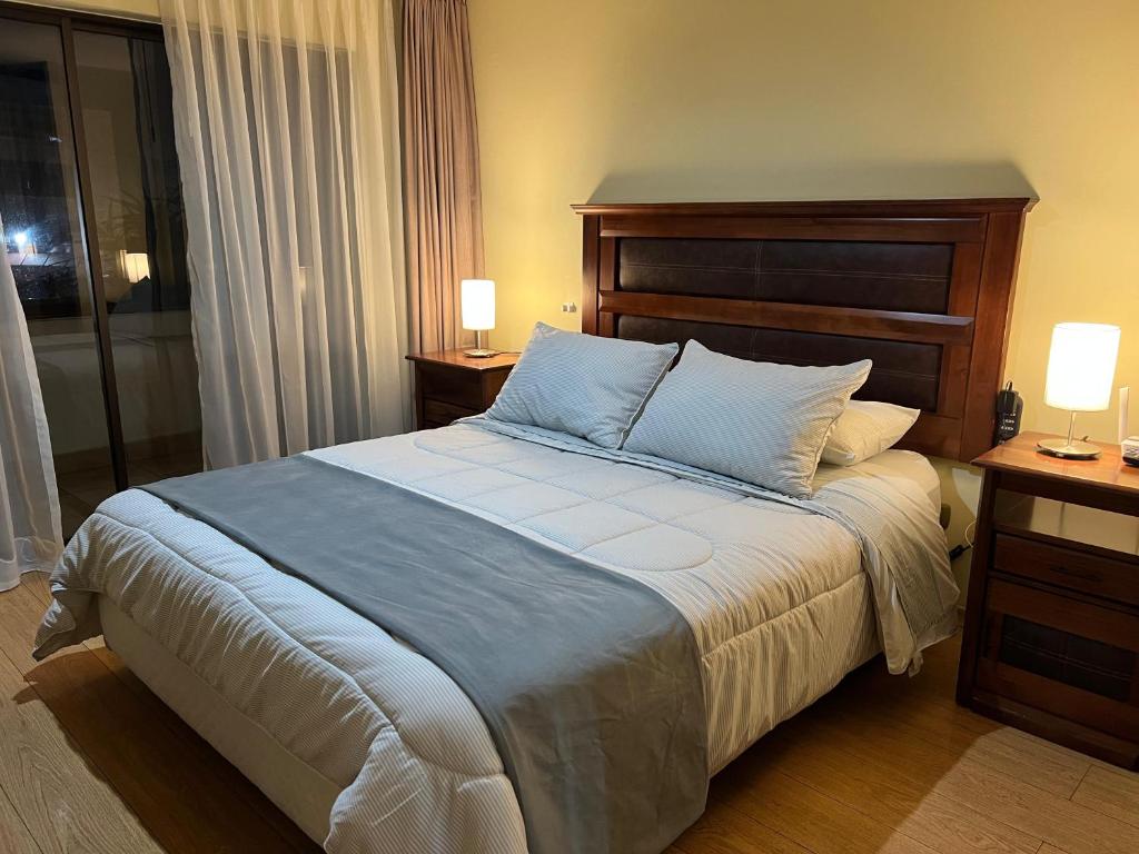 Un dormitorio con una cama grande con dos mesas y dos lámparas. en Departamento Coyancura, en Santiago