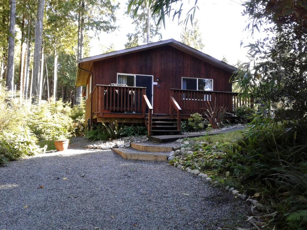 a cabin in the woods with a porch and stairs at Little Bear Cabin at Raven's Moon in Ucluelet
