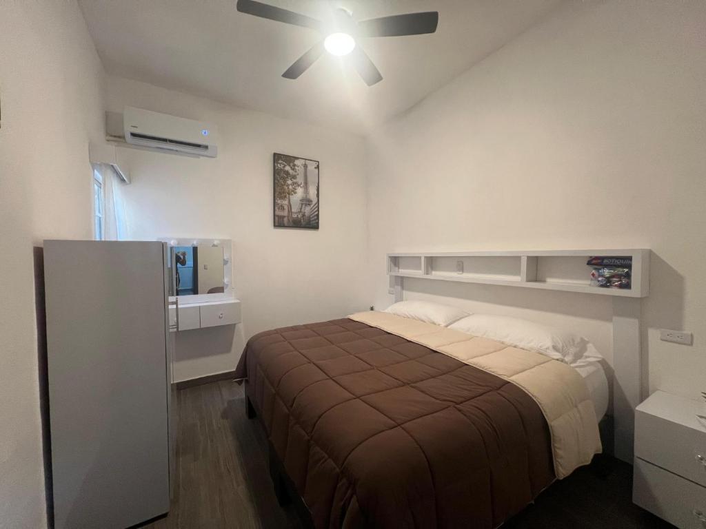 Un dormitorio con una cama y un ventilador de techo. en Alameda Suites & CAS - Centro Monterrey, en Monterrey