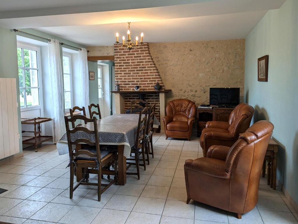 un soggiorno con tavolo, sedie e camino di Maison rénovée près d'Orléans avec animaux admis - FR-1-590-583 a Vennecy