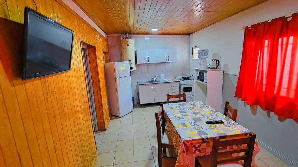 a kitchen with a table and a television on a wall at Departamento ITATI in General Alvear