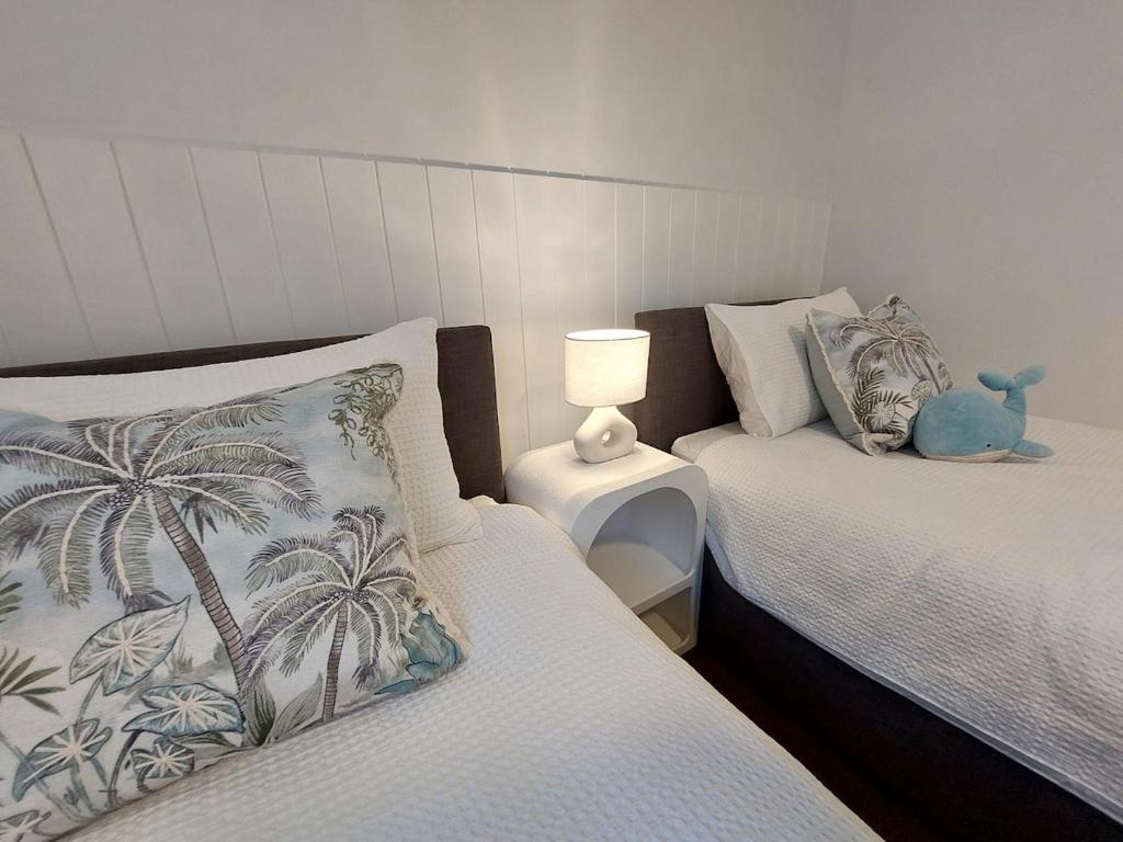 ein Schlafzimmer mit 2 Betten und einem ausgestopften Tier auf einem Nachttisch in der Unterkunft Charming Coastal Cottage Retreat in Vincentia