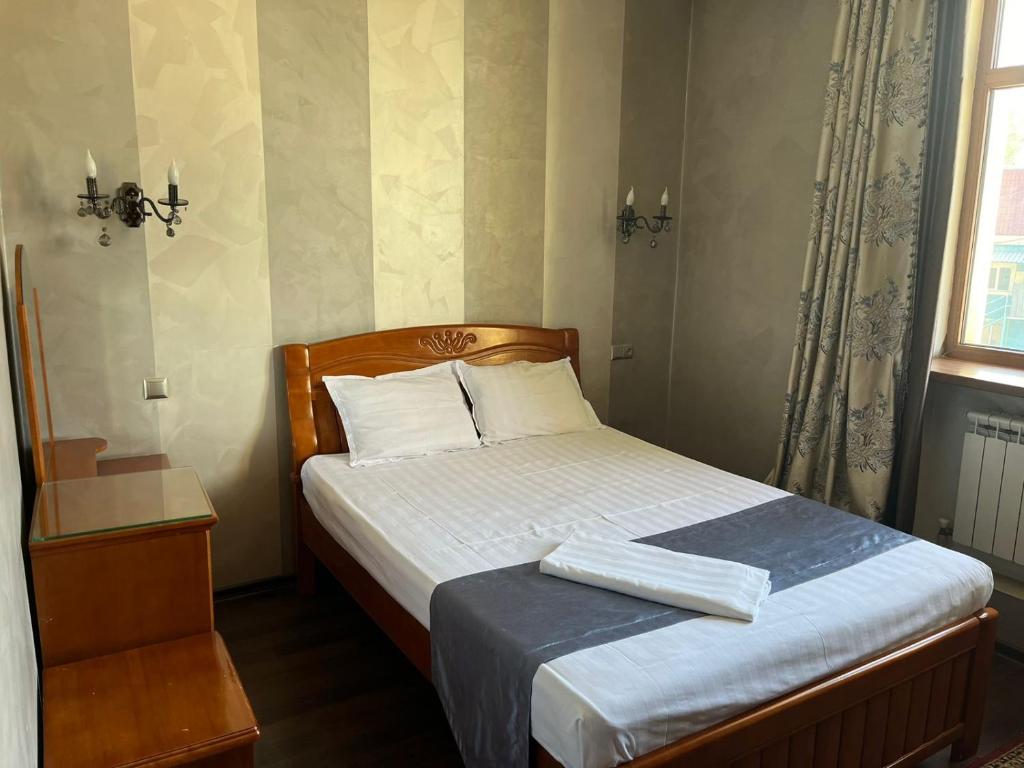 a small bedroom with a bed with white sheets and a window at Ak zhol in Almaty