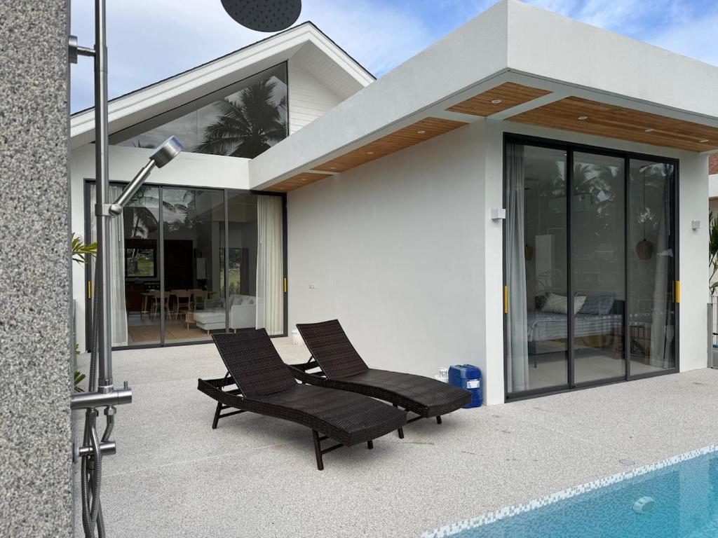 zwei Stühle auf einer Terrasse neben einem Haus in der Unterkunft Modern Pool Villa Escape in Koh Phangan in Ko Phangan