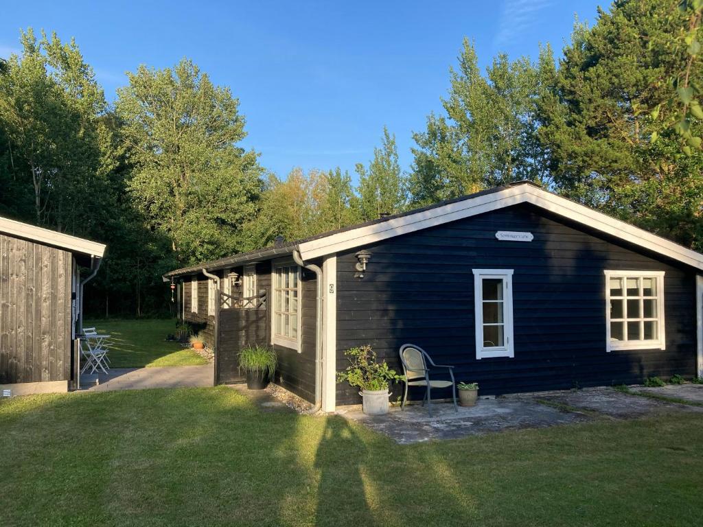 a small blue house with a chair in a yard at Summerhouse Near Marielyst Beach With Large Garden in Marielyst