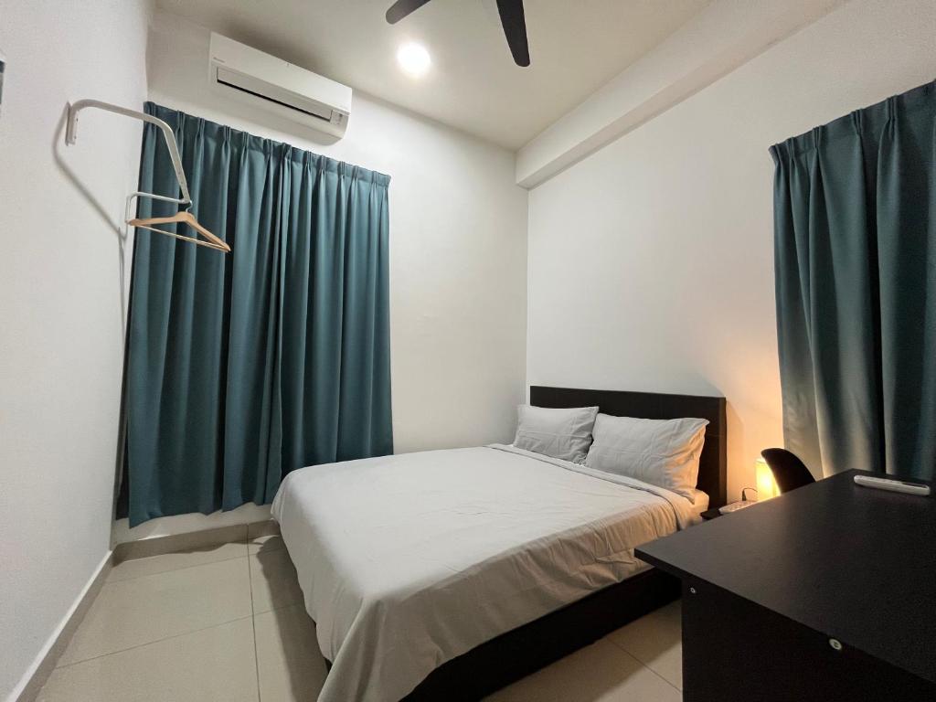 a bedroom with a bed and a desk and a green curtain at Goldenstay Mutiara Ville Cyberjaya in Cyberjaya