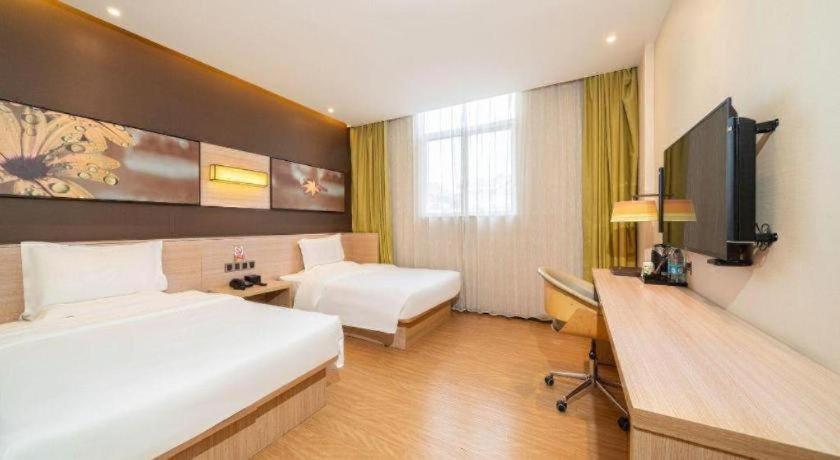 a hotel room with two beds and a desk at IU Hotel Xi'an Gulou Huimin Street Qiaozikou Metro Station in Xi'an