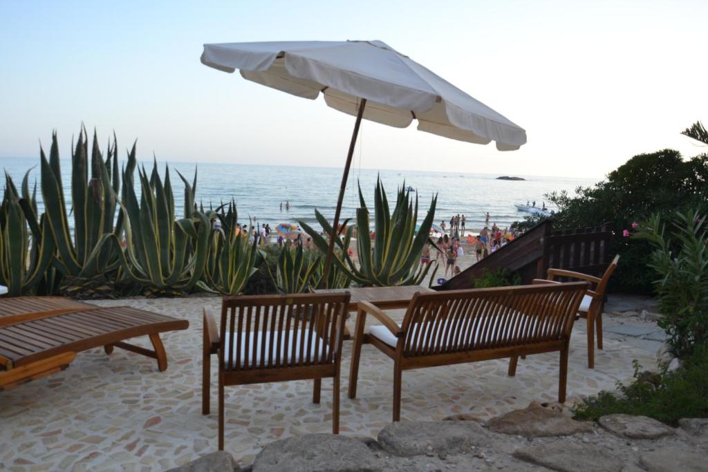 dos bancos y una sombrilla frente a la playa en Villa Venere Apartment, en Realmonte