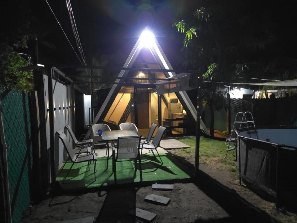 a house with a table and chairs and a light at Cozy A-Frame Beach Cabin Sihu-A Casa in Las Piedras