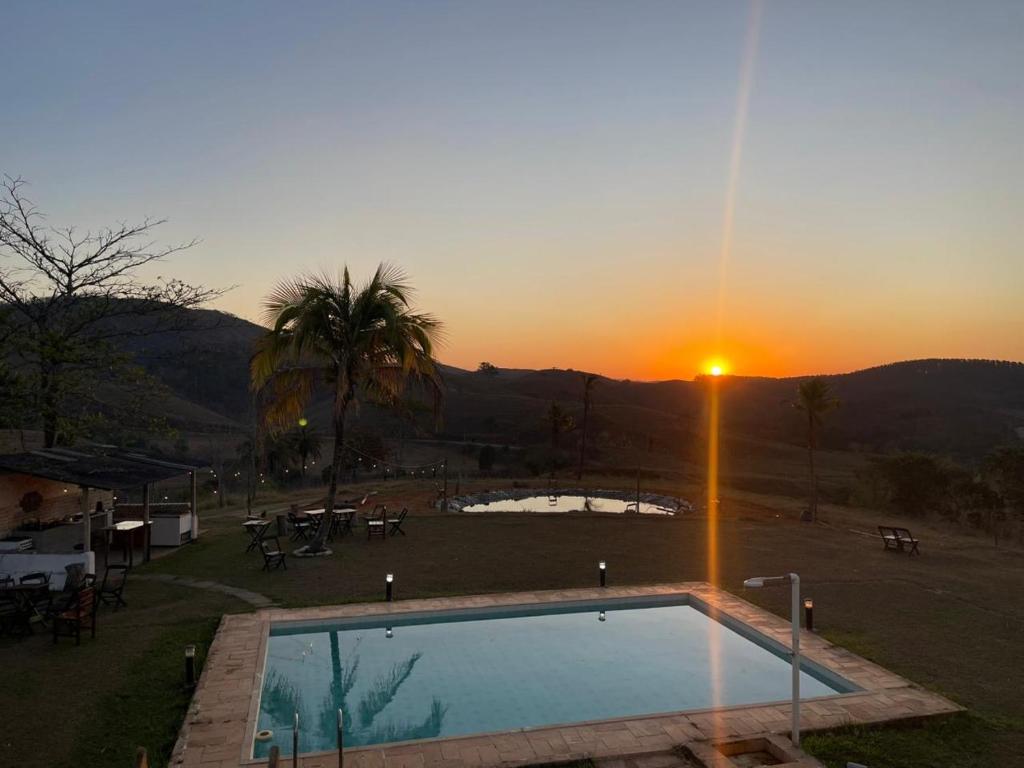 una piscina con puesta de sol en el fondo en Espaço fazendinha por do Sol da piscina, en Paty do Alferes