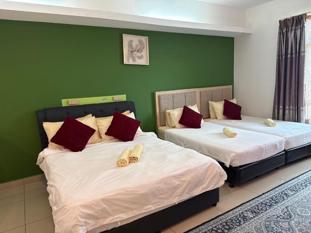 deux lits dans une chambre aux murs verts dans l'établissement The Viana Apartment 3, à Kota Bharu