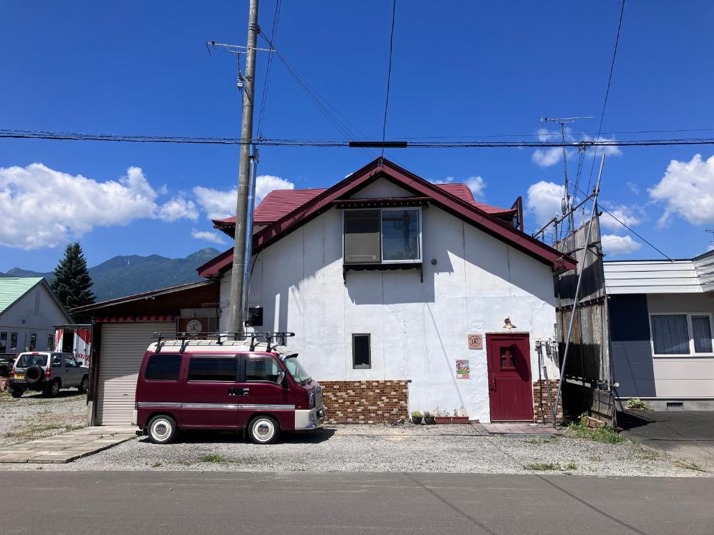 富良野市にあるMOTORYOKAN Guesthouse & Cafeの白い家の前に停まった赤いバン