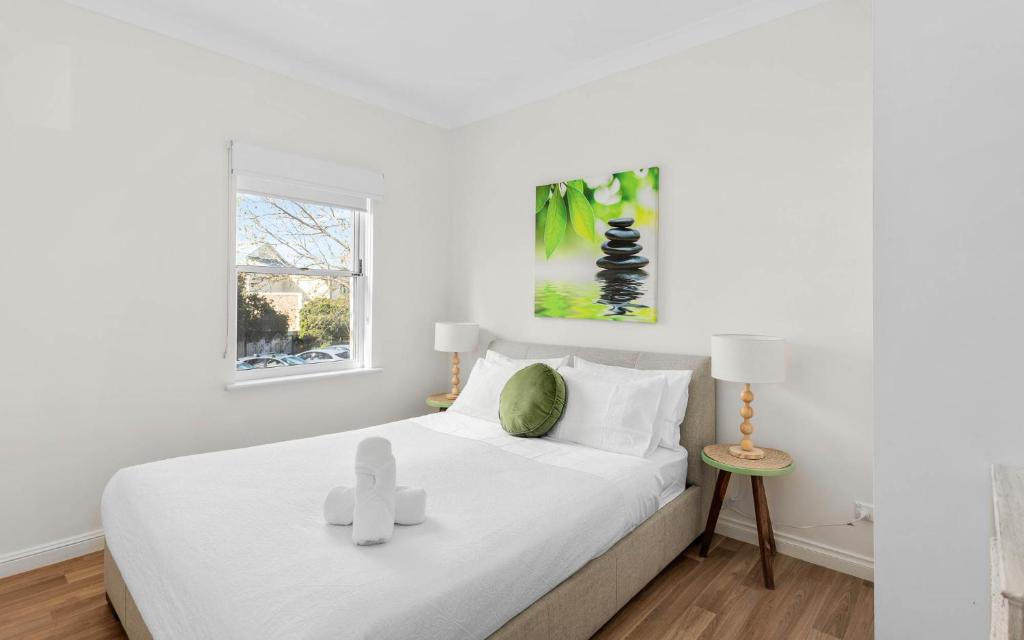 a white bedroom with a bed with two crosses on it at Sea Breeze at Smugglers Inn in Victor Harbor