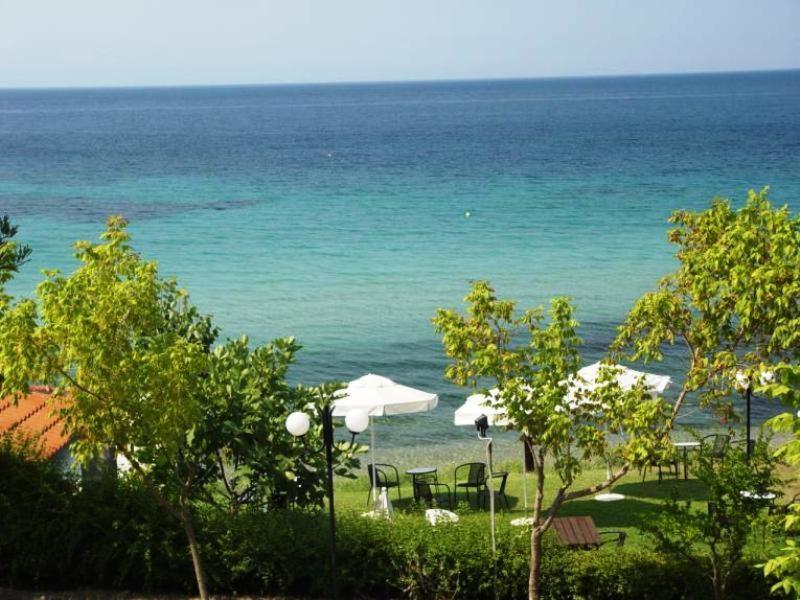 una spiaggia con sedie e ombrelloni e l'oceano di Para Thin Alos Inn a Néos Marmarás
