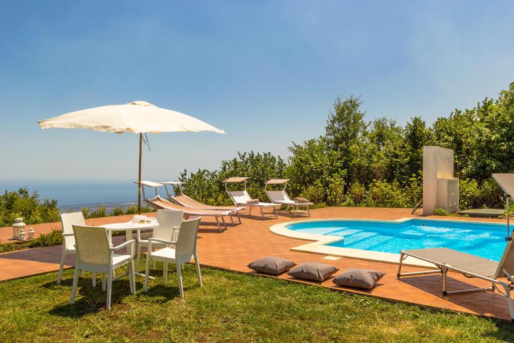 un patio con mesa, sillas y piscina en Le Vignoble Charming Maison, en Mascali