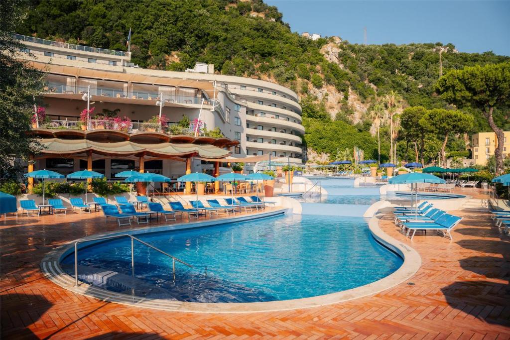 a hotel with a swimming pool with chairs and umbrellas at Hilton Sorrento Palace in Sorrento