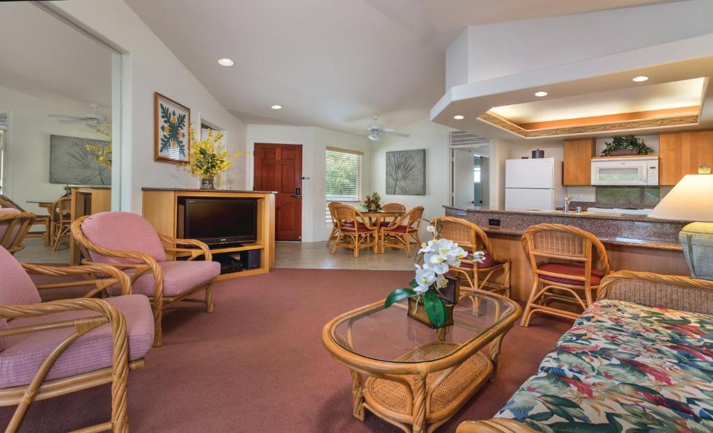 a living room with chairs and a table and a kitchen at Club Wyndham Bali Hai Villas in Princeville
