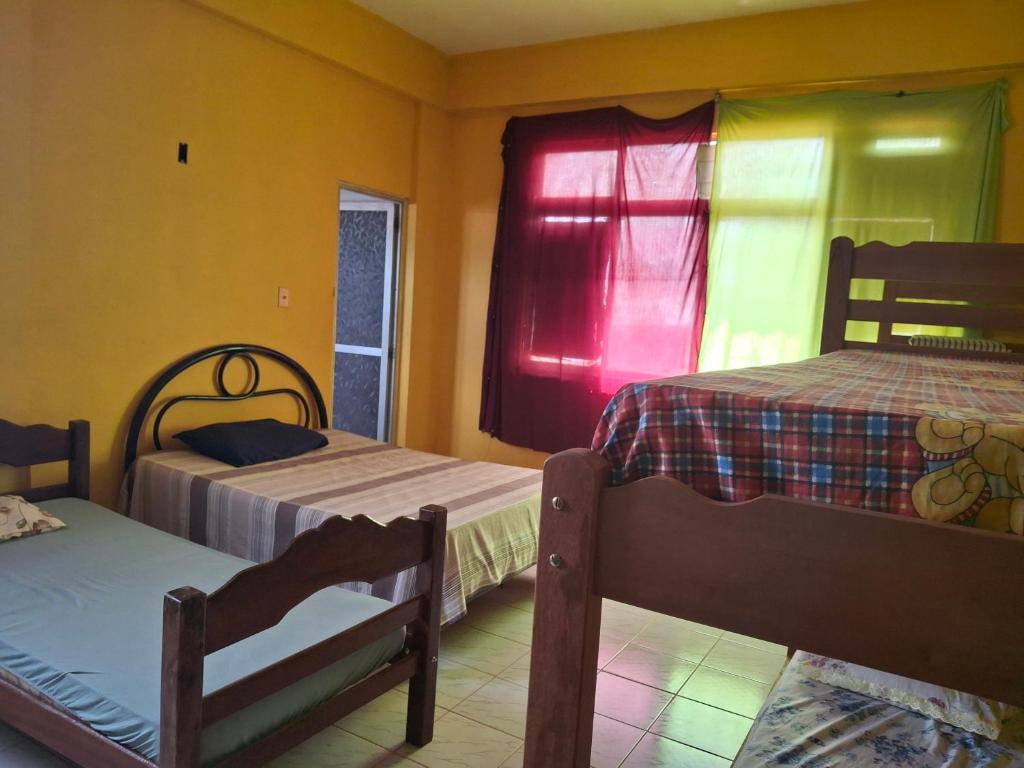 ein Schlafzimmer mit 2 Betten und einem Fenster mit einem roten Vorhang in der Unterkunft Aconchego benevides Barcelona in Benevides