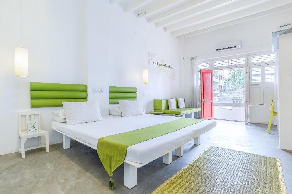 een slaapkamer met een groot wit bed met groene accenten bij Itsy By Treebo - Red Lotus Heritage Promenade Beach in Pondicherry