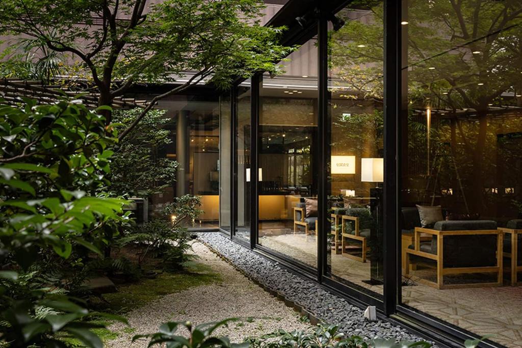a glass entrance to a building with tables and chairs at Loisir Hotel Classic Garden Kyoto Sanjo in Kyoto