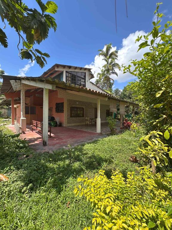 a house with a porch and a grass yard at Casa Alojamiento La Cascina in Iquitos