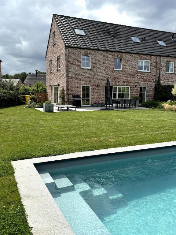 a brick house with a swimming pool in the yard at Brabant house with pool in Rixensart
