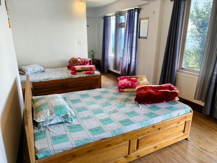 una camera da letto con due letti in una stanza di Petratos Homestay a Kalimpong