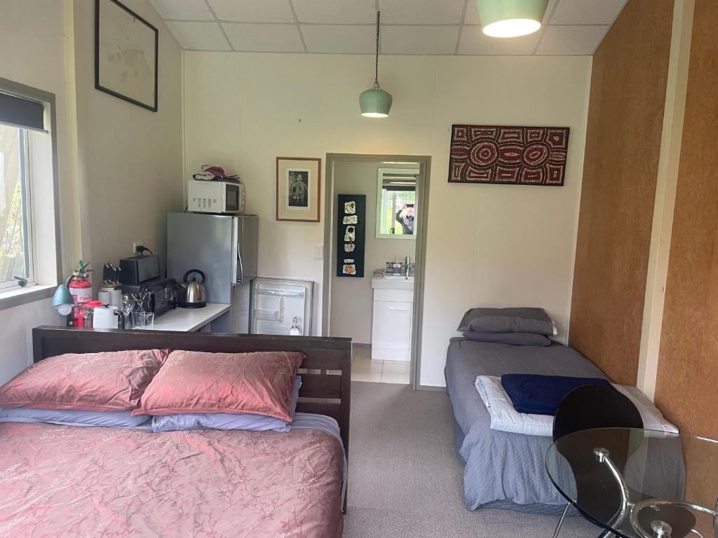 a bedroom with two beds and a kitchen with a refrigerator at Ruapehu country lodge in Ohakune