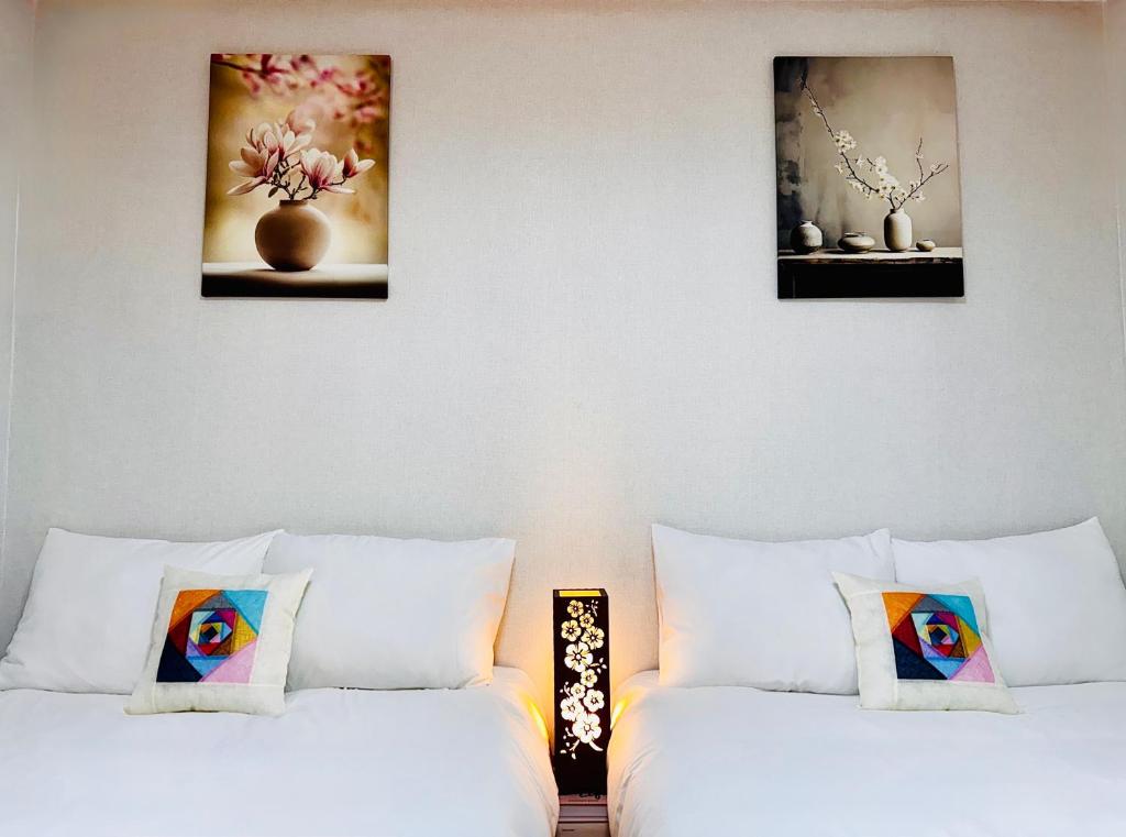 two beds in a room with paintings on the wall at Seoul Gate Stay in Seoul