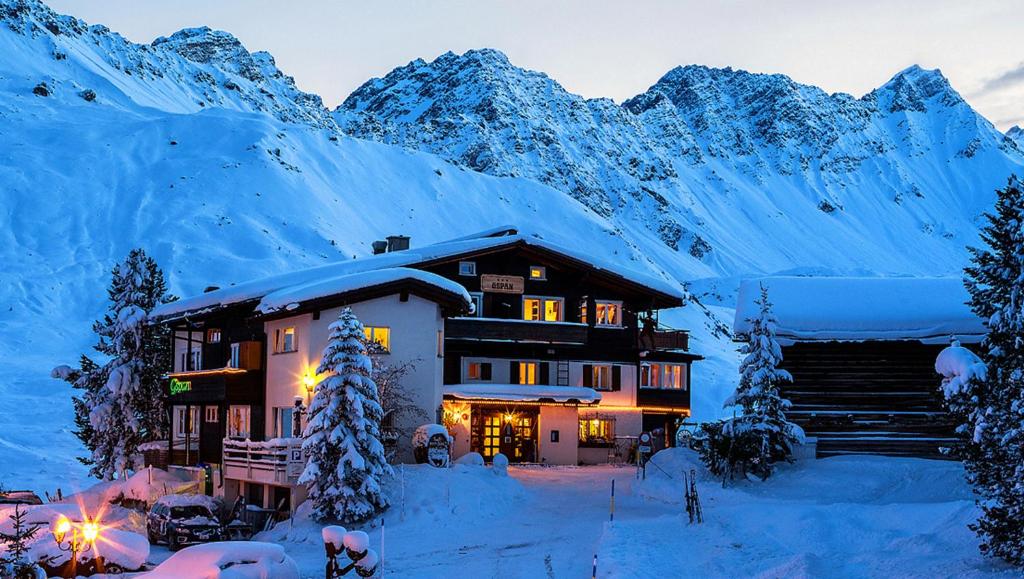 a lodge in the snow with mountains in the background at Hotel Gspan in Arosa
