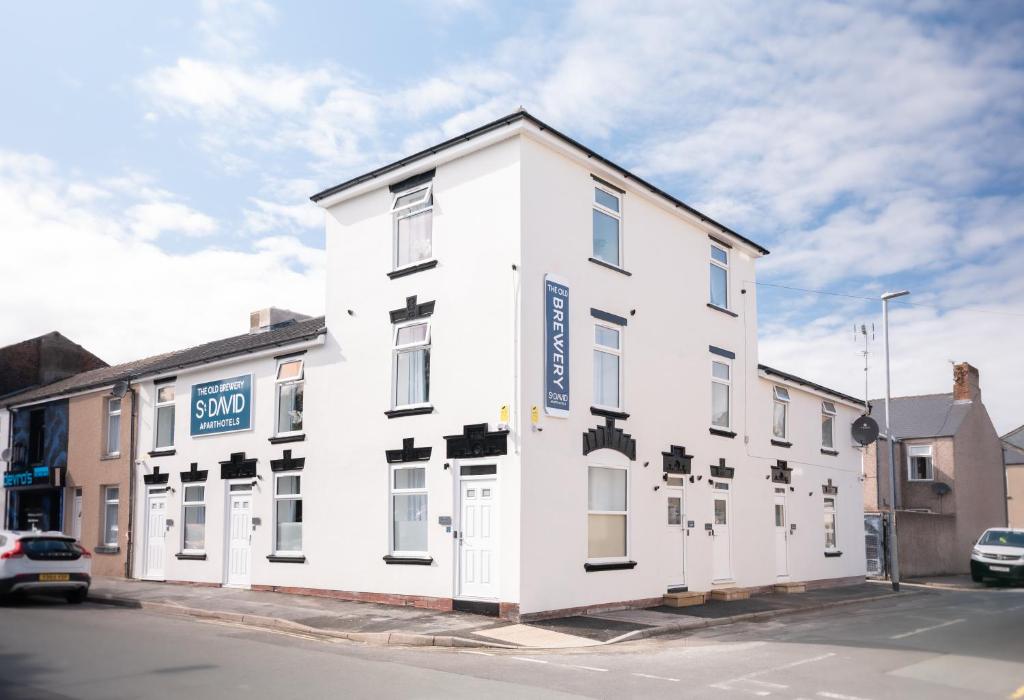a white building on the corner of a street at The Old Brewery - A St David Aparthotel in Barrow in Furness