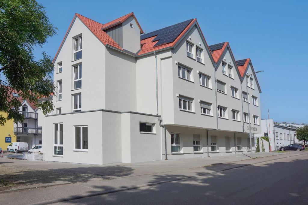 ein weißes Gebäude mit rotem Dach an einer Straße in der Unterkunft SMARTHOTEL Aalen in Aalen