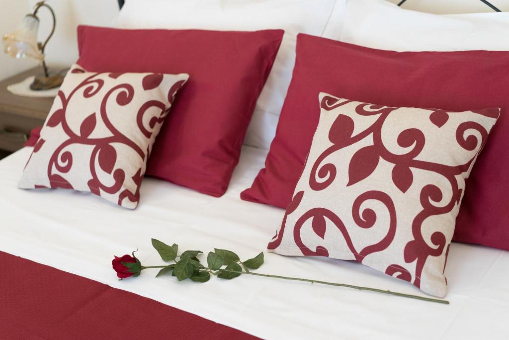 カターニアにあるB&B Palazzo Tornabeneのベッド(赤と白の枕、バラ付)