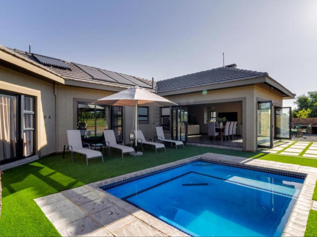 a backyard with a swimming pool and a house at Tenkudu Bush Lodge in Dinokeng Game Reserve
