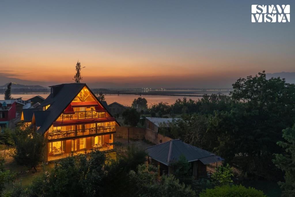 a house on a hill with the sunset in the background at StayVista at Emaarat Chalet with BBQ & Bonfire in Srinagar