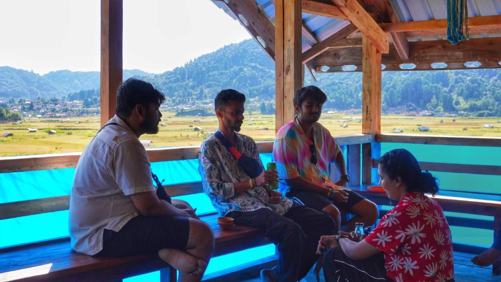 a group of people sitting on a bench looking at a field at Stargaze Backpackers Ziro in Ziro